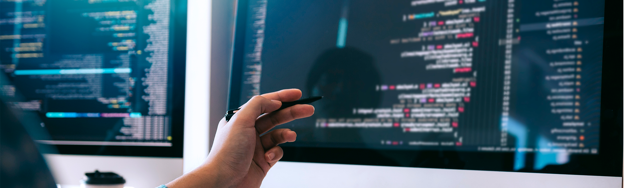 Imagen de una persona trabajando con varios monitores que muestran código y elementos de desarrollo web