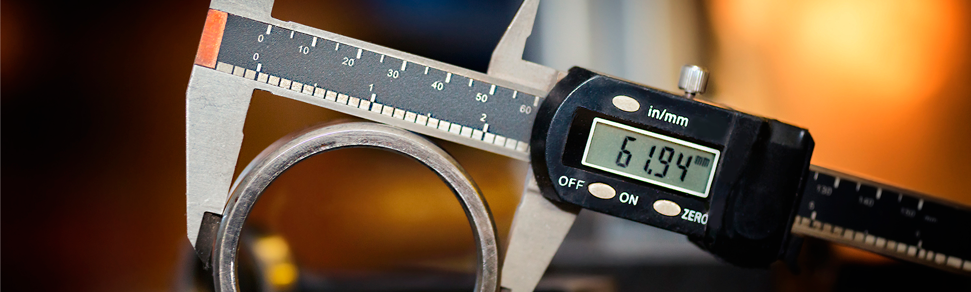 Imagen de un calibrador digital midiendo una pieza metálica cilíndrica sobre una mesa de trabajo